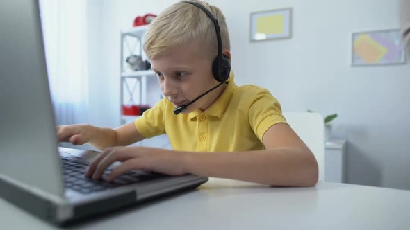 Little Gamer in Headset Playing on Laptop Mom Putting Books on Desk and Scolding