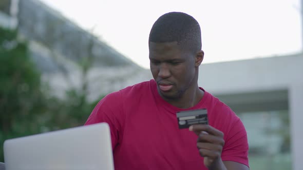Afro-American Man Typing on Laptop, Paying with Credit Card