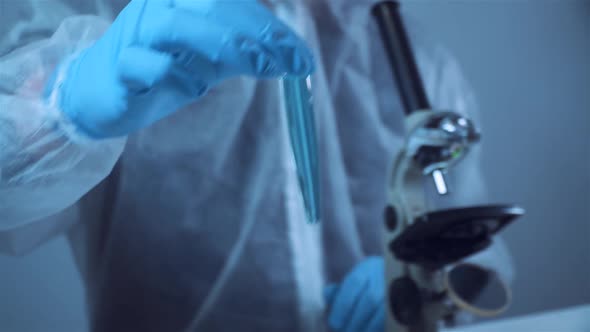 Biochemistry Laboratory Research Chemist in Protective Suit Analyzing Blue Sample in Laboratory with