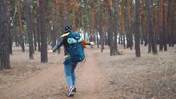 Happy Tourist with Backpack on Forest Pine Trees