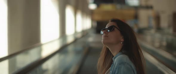 Woman with sunglasses looking around while standing on a moving walkway