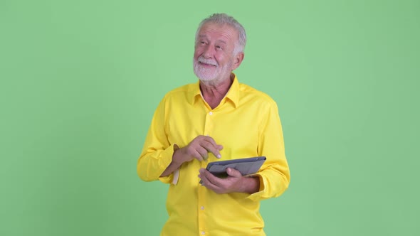 Happy Senior Bearded Businessman Thinking While Using Digital Tablet