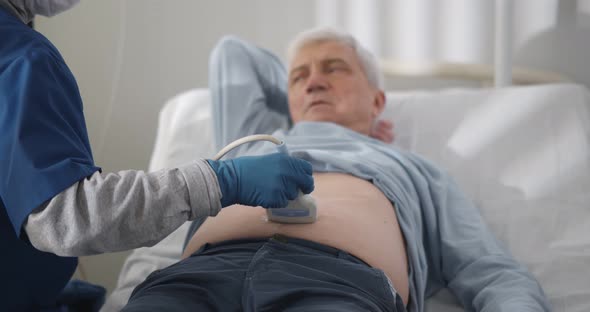 Senior Man Getting Ultrasound Examination on Abdomen From Doctor