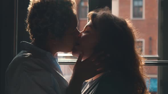 Couple of Excited Multiethnic Lesbians Kissing Passionately in Front of Window