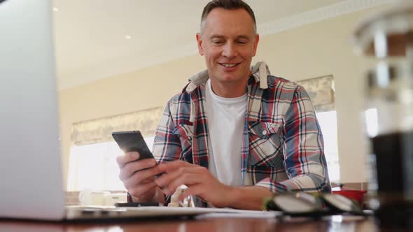 Mature man using mobile phone in kitchen 4k