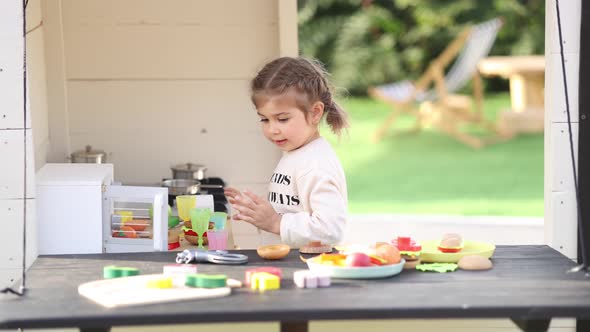 Happy Little Girl Playing on Toy Kitchen on Wheels