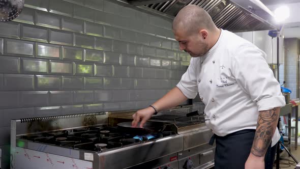 Cook in Restaurant Kitchen Frying Meat on Stove on a Pan