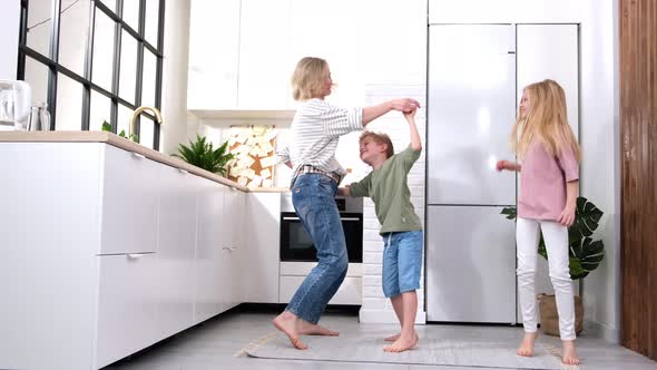 Excited Mom or Babysiter and Two Kids Boy and Girl Jumping Dancing Laughing in Modern Scandinavian