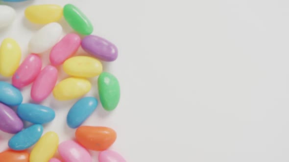 Video of close up of multi coloured sweets with copy space over white background