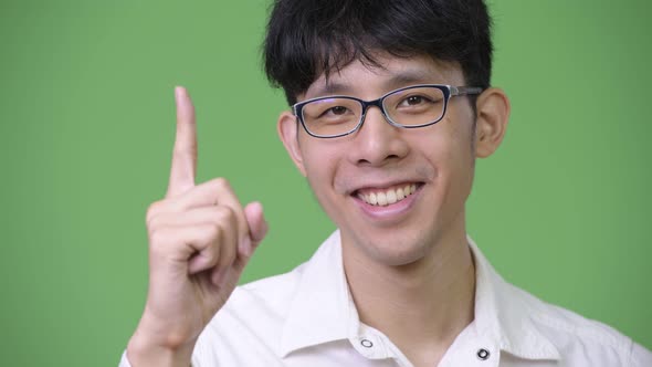 Young Asian Businessman Smiling While Pointing Up