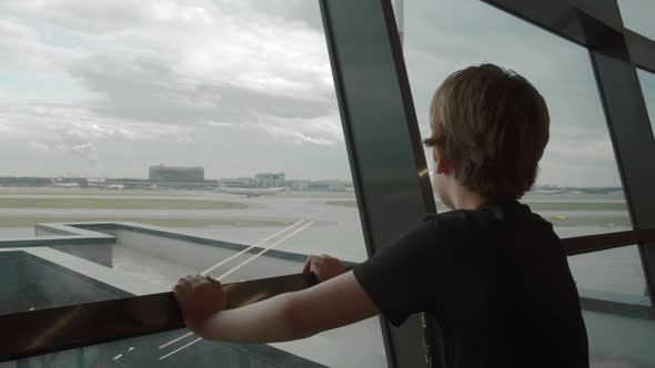 Young traveller likes watching departing planes at the airport