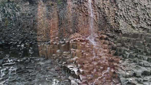 Trucking shot of waterfall flowing down basalt columns Studlagil Canyon, Iceland.