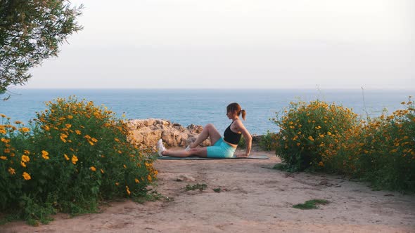 A Young Woman in Sportswear Exercising on Yoga Mat By the Sea