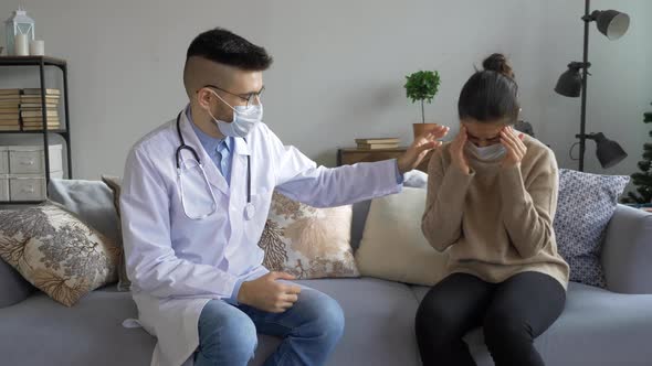 Male doctor in a protective suit listens to the breath of an elderly sick woman