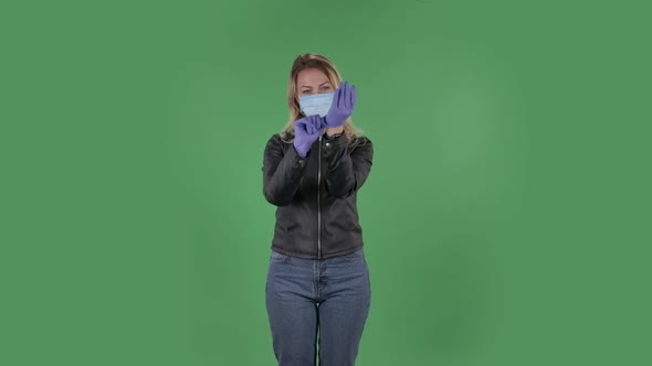 Portrait of Beautiful Young Woman in Medical Mask Is Looking at Camera and Puts on Rubber Gloves