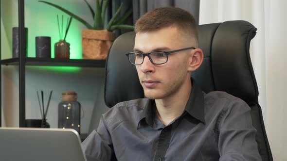 Businessman is using notebook at workplace desk. Male freelancer works on laptop at home office