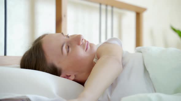 Woman Waking Up in Her Bed Fully Rested. Woman Stretching in Bed After Wake Up.