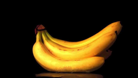 Super Slow Motion a Bunch of Bananas on a Black Background Falls on the Table