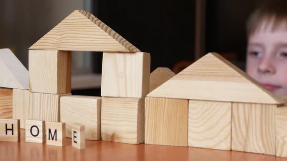 Caucasian preschooler boy enthusiastically plays at home, builds a building from cubes