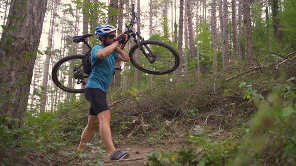 Young Mountain Biker Climbs on a Path in a Forest