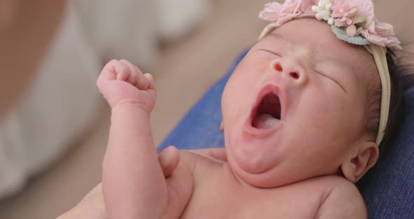 Mother Decorating Flower To Daughter. Lovely Asian Newborn Baby Yawning On Mother's Lap.