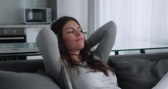 Serene Attractive Young Woman in Headphones Resting on Couch Taking Deep Breath of Fresh Air Holding