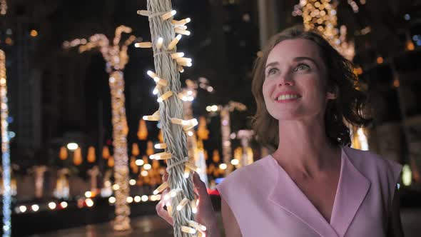 The Girl Gently Touches the Glowing Lights on a Palm Tree in the Night City of Dubai