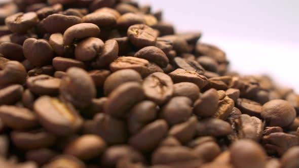 Close-up of roasted coffee beans rotating on a white background