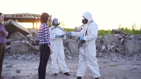 Portrait Scientists in Protective Suits and Masks and Dosimeter Measure Radiation and Affected