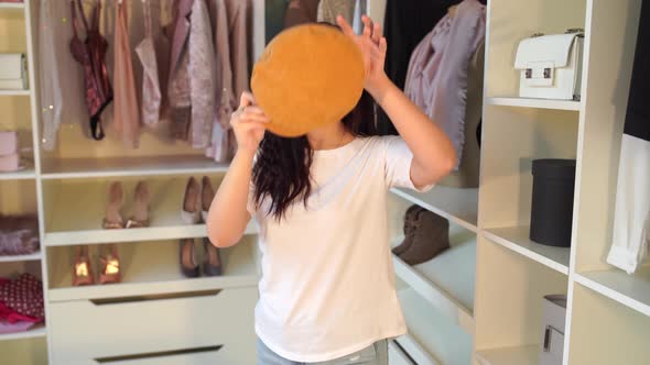 A Woman Tries on a Hat in the Dressing Room. Female Try on Hat and Looking in Mirror. Happy Yound