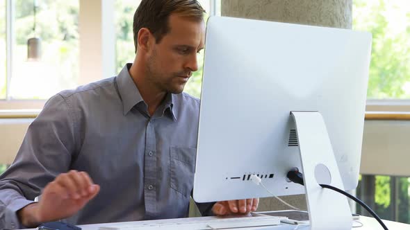 Male executive talking on mobile phone while working at desk 