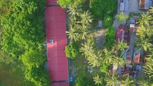 Aerial flight over local village huts and forest on island in Malaysia, birds eye perspective moving