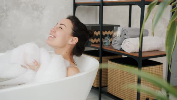 Slow Motion of Female Student Enjoying Warm Bath with Foam Smiling Relaxing at Home