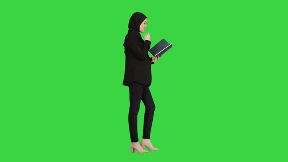 Muslim Businesswoman Reading Her Business Planner While Walking To the Meeting on a Green Screen