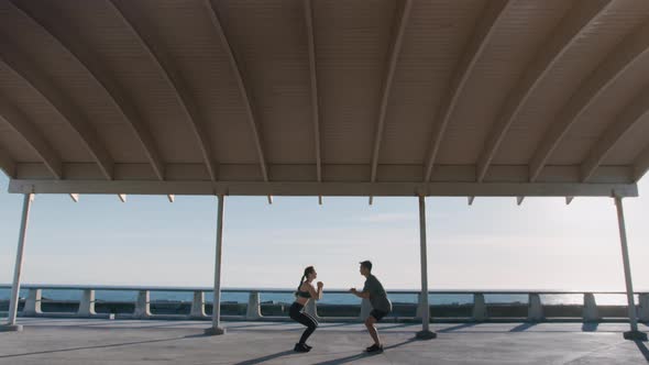 Young Sporty Couple Doing Squats Outdoors in City