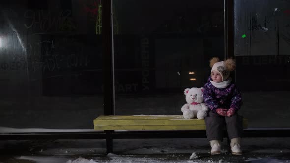 Girl Sits Alone at Night at the Bus Stop