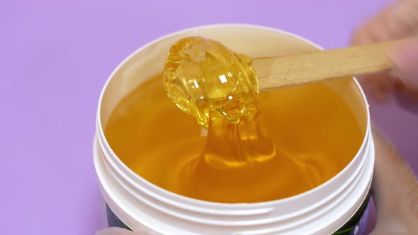 Sugar paste or honey wax for hair removal, dripping from wooden wax sticks - depilation and beauty