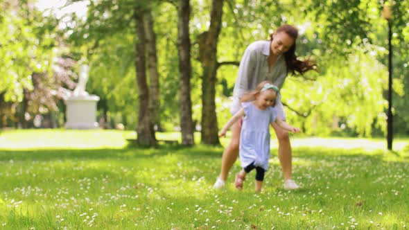 Happy Mother with Little Daughter Playing at Park