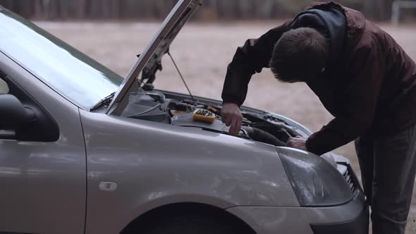Man repairing broken car.