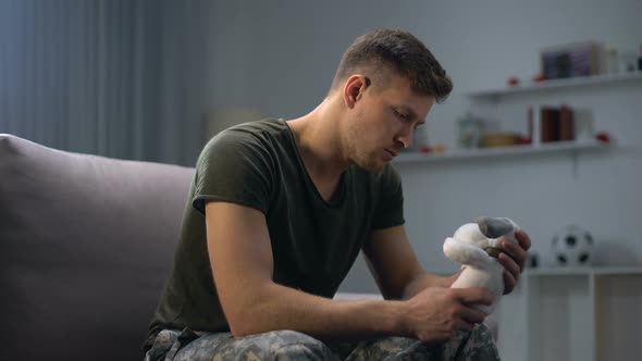 Melancholic Male Soldier Holding Toy Dog