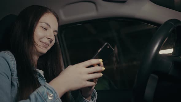 Woman Uses an Application on His Phone While Sitting in the Car in the Parking Lot