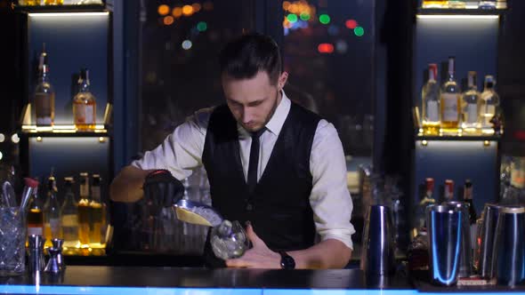 Barman Putting Ice in Glass Making Cocktail at Bar