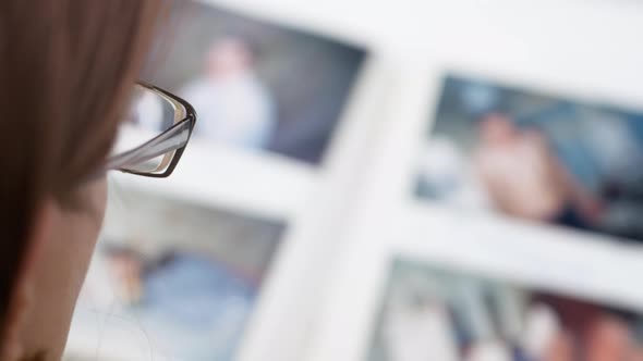 A woman is looking at an album with photographs. Defocus on the photo.