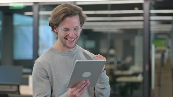 Portrait of Young Businessman Celebrating Success on Tablet