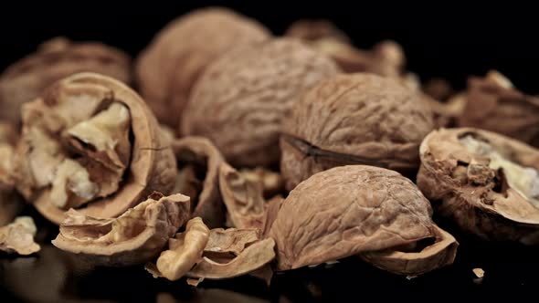 Lot of Walnuts in the Shell are Spinning on a Black Background