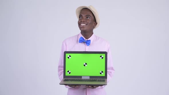 Young Happy African Tourist Man Thinking While Showing Laptop