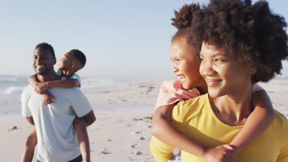 Smiling african american family embracing and walking on sunny beach