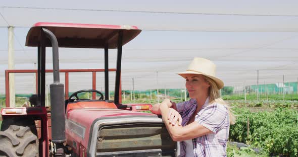 Video of happy caucasian woman standing in front of tractor