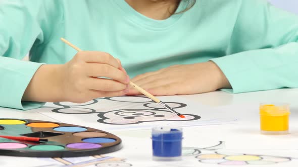 Little Girl Sits at the Table and Paints Her Drawing. Close Up