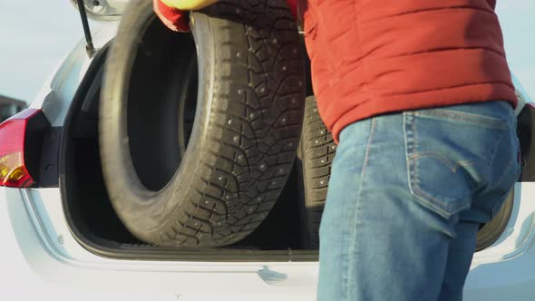 A man puts in a car trunk winter tires